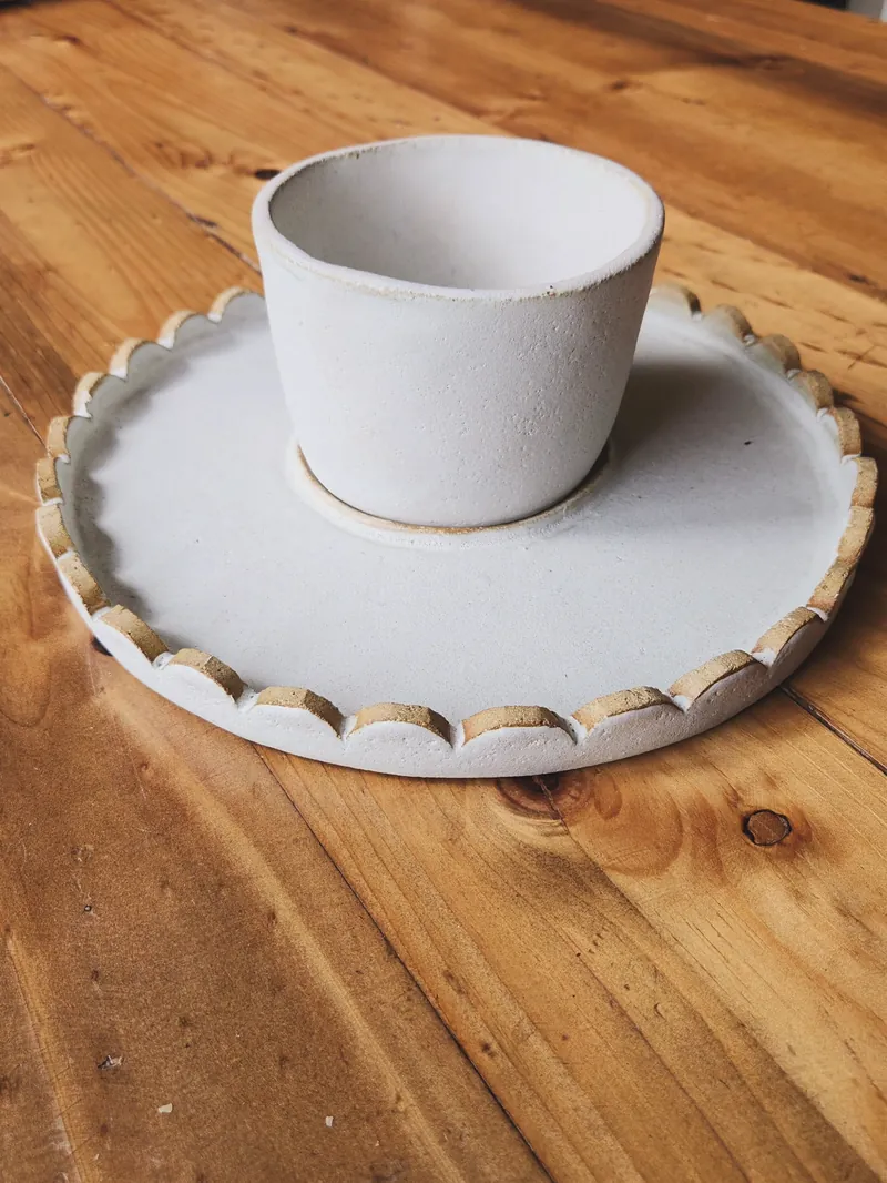 Plato dual con su pocillo, sobre una mesa de madera