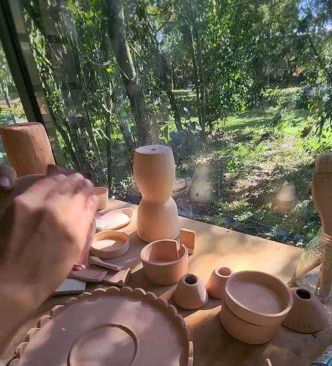 Mesa del taller con piezas de gres secándose frente al bosque