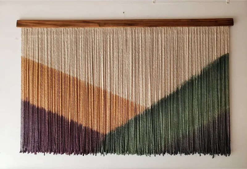 Mural de macramé teñido en tonos tierra, verde y morado